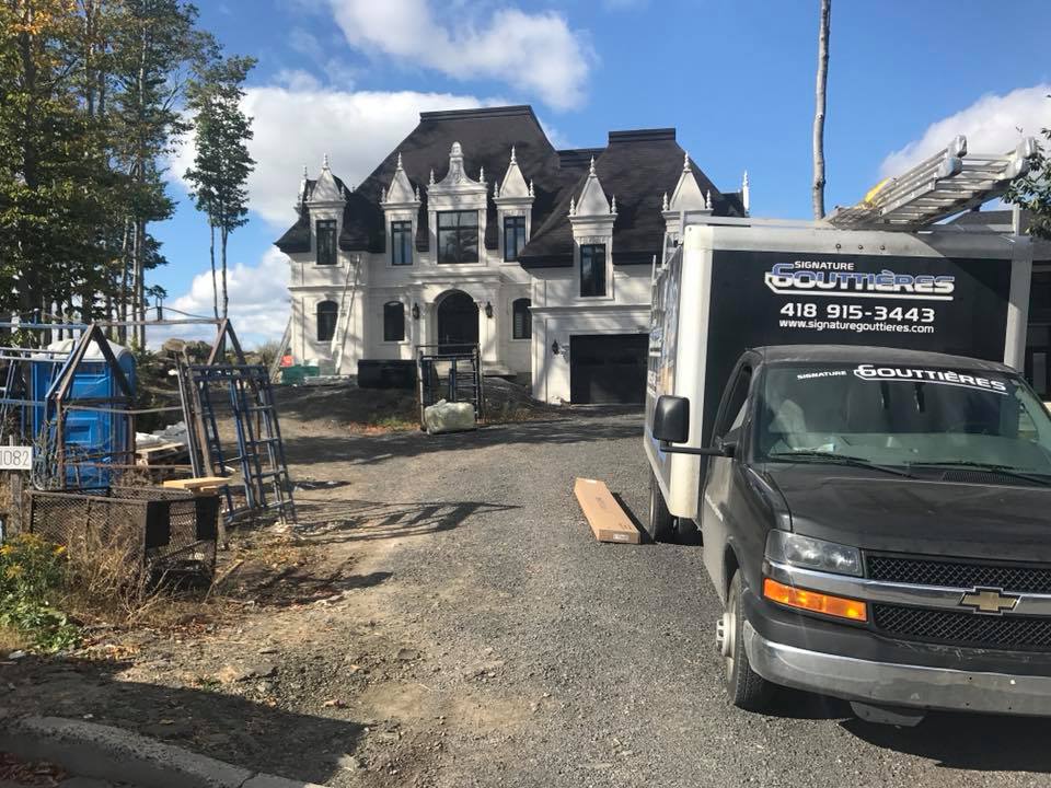 Véhicules de service stationnés lors de travaux d’installation de gouttières  sur la Rive-Sud et la Rive-Nord de Québec
